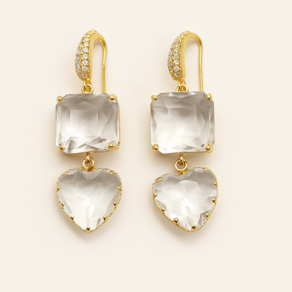 Gold earrings with clear gemstones on a beige background