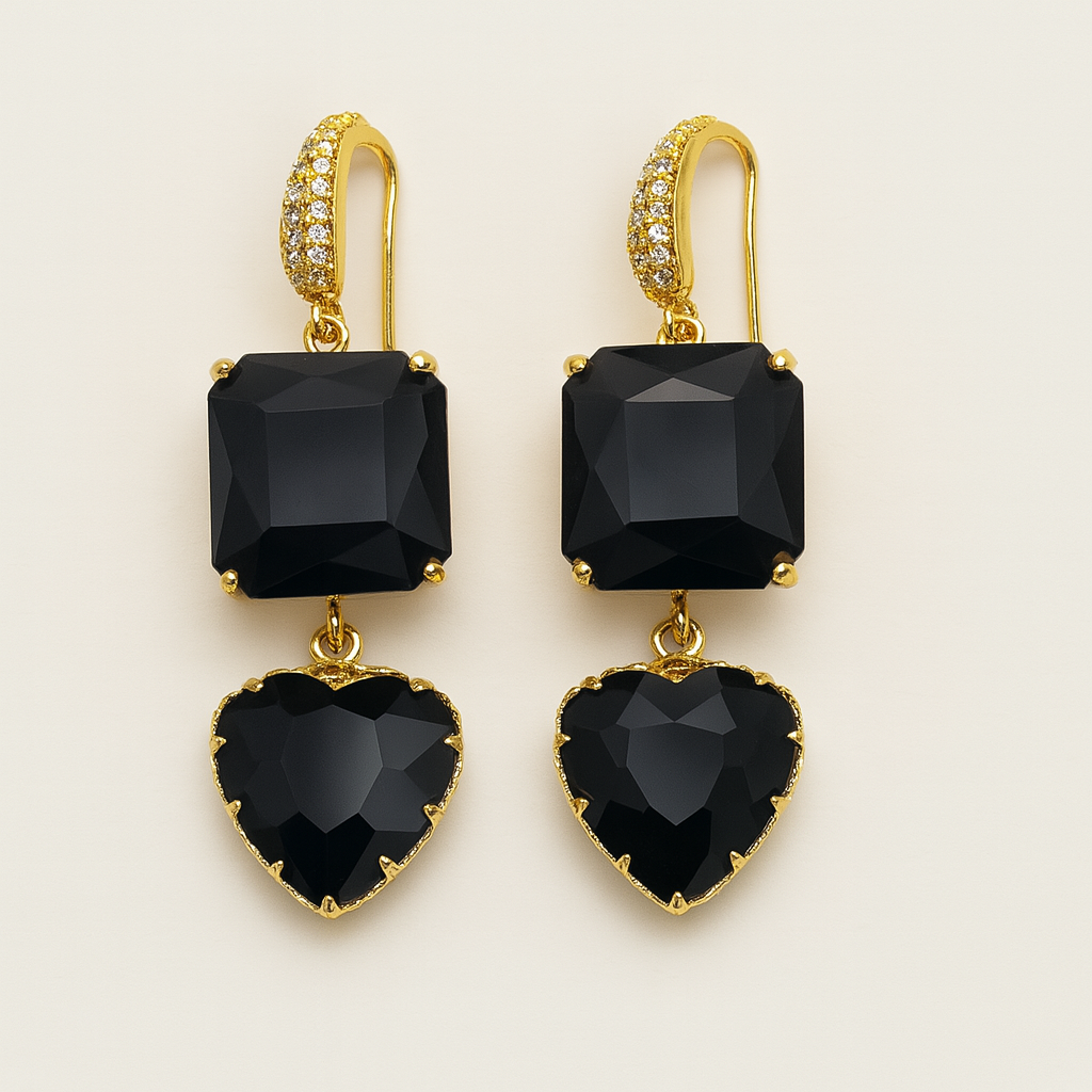 Gold earrings with black heart and square stones on a beige background