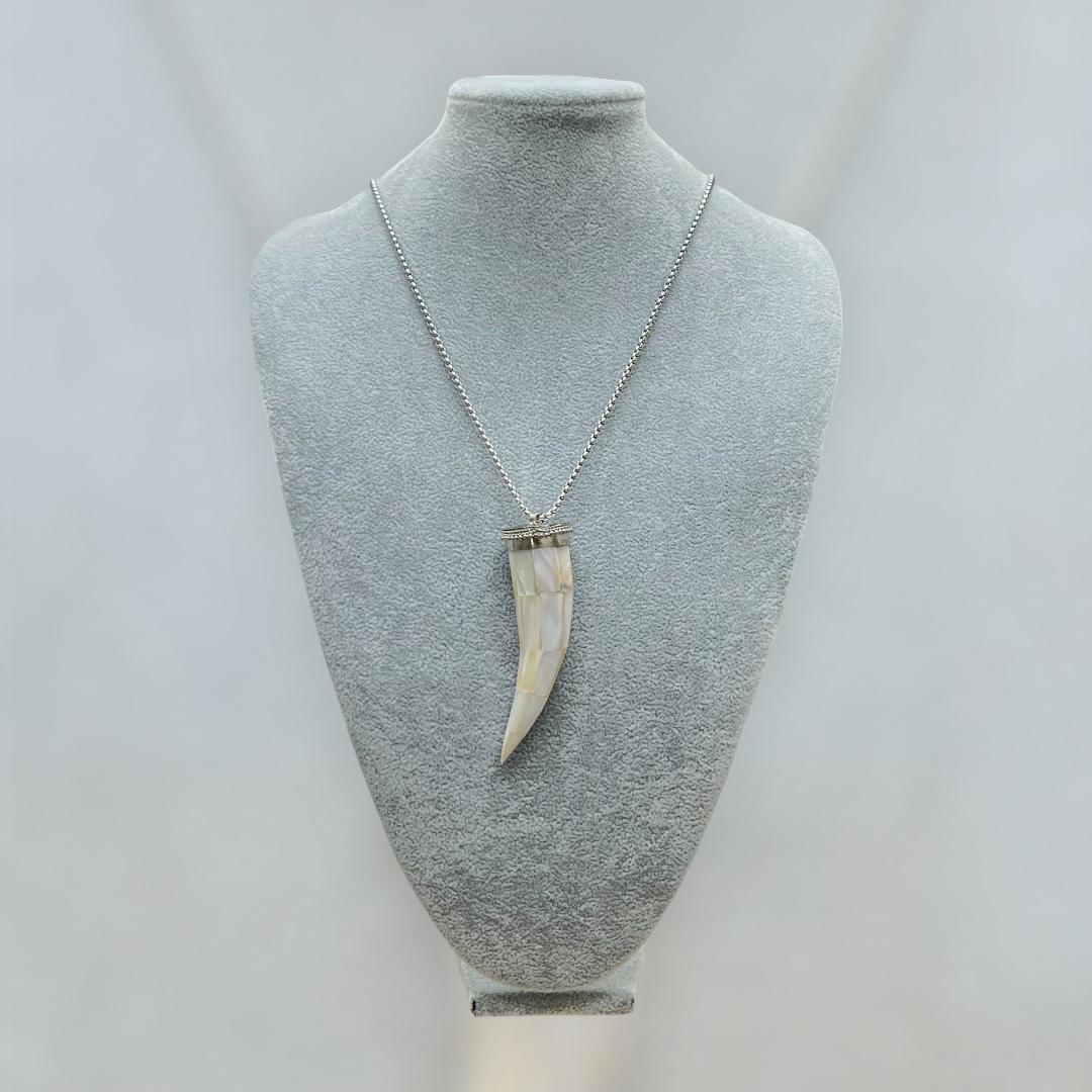 Necklace with a tusk pendant on a mannequin bust against a light gray background