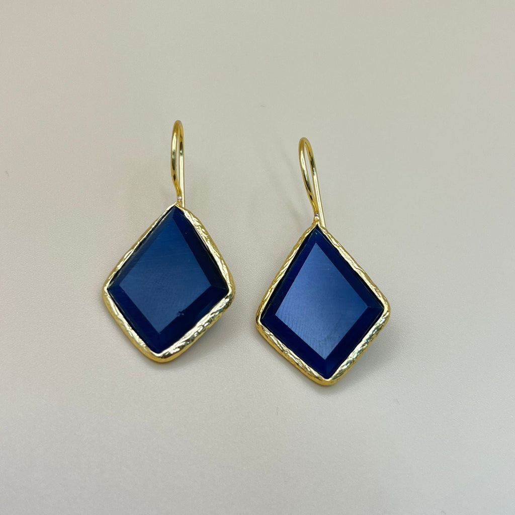 Gold earrings with blue gemstones on a light gray background