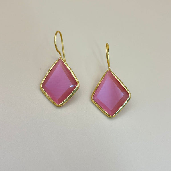 Pair of pink earrings with gold frames on a beige background