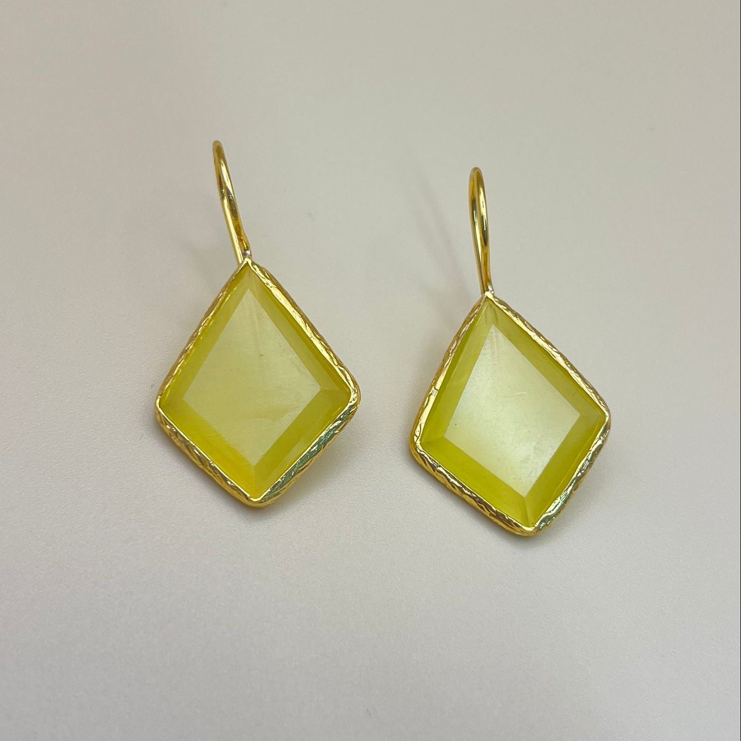 Gold-framed yellow gemstone earrings on a light gray background
