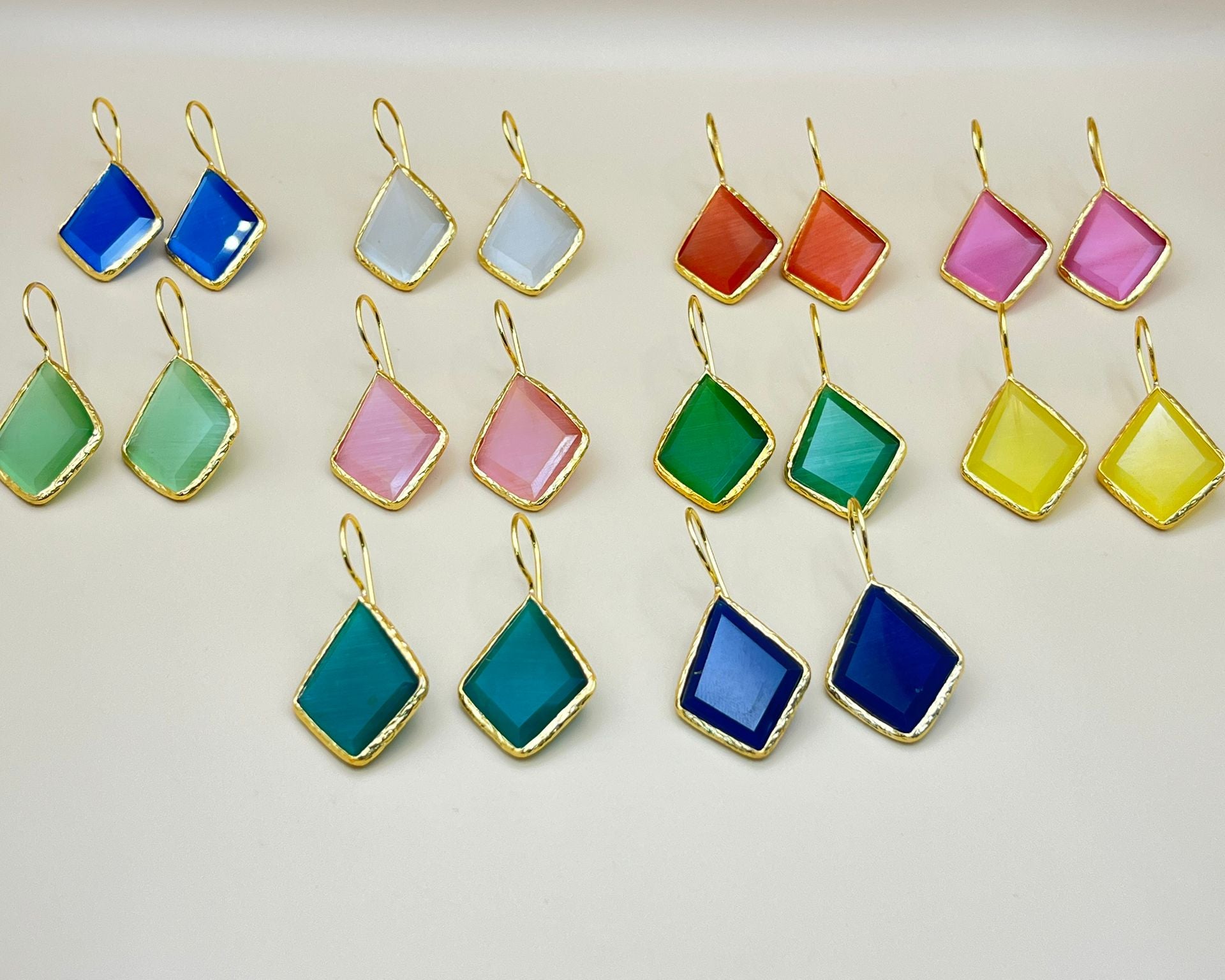 Set of colorful square-shaped earrings with gold frames on a light background