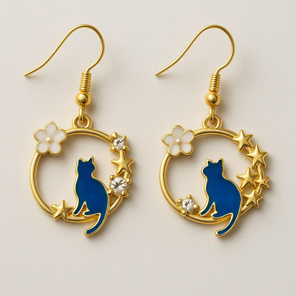 Pair of earrings with blue cat design, gold hoop, and star elements on a light background